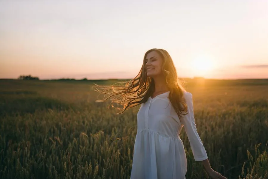 Mulher sorrindo em paz ao sol.